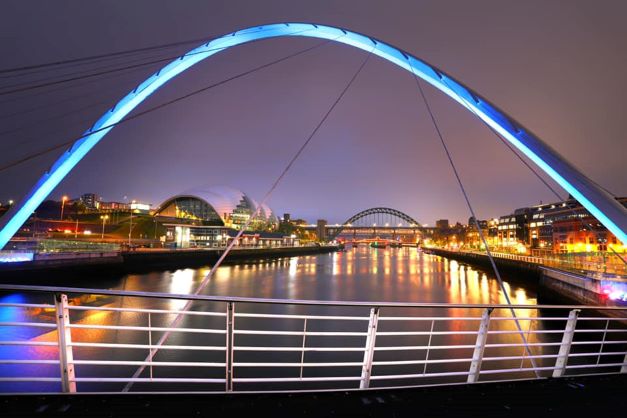 Image shows Newcastle Quayside at night with the bridges in the foreground.