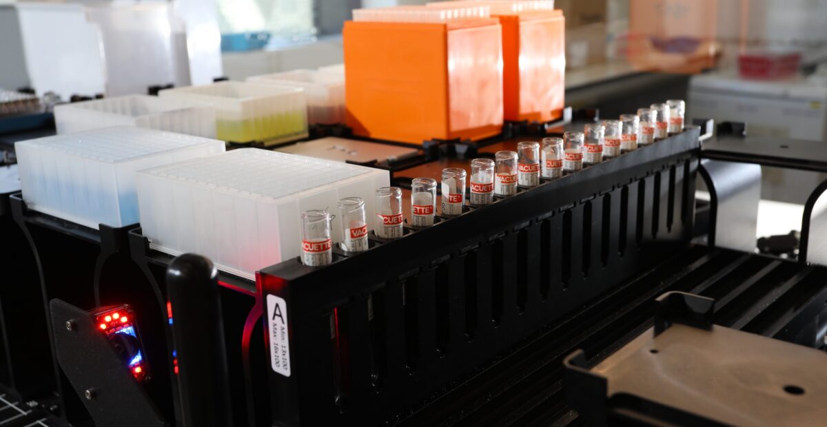 A close up view inside a large piece of lab equipment containing test tubes lined up in a rack.
