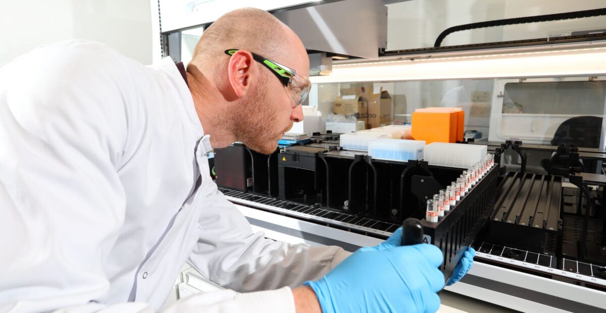 Dr Simon Rock putting a rack of test tubes into a large piece of lab equipment.