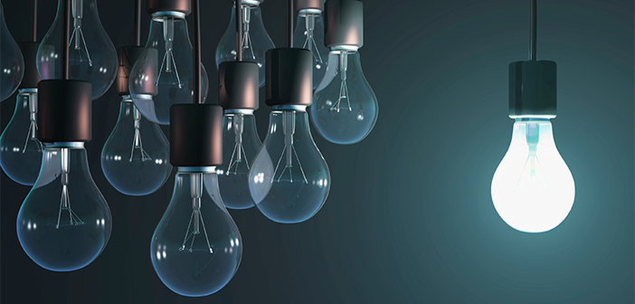 The image shows a group of lightbulbs switched off with one shining brightly.