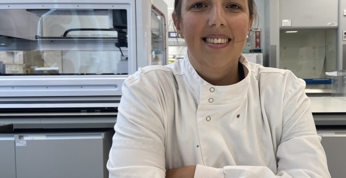 Portrait of Amanda Winter wearing a white lab coat while sat at a bench.