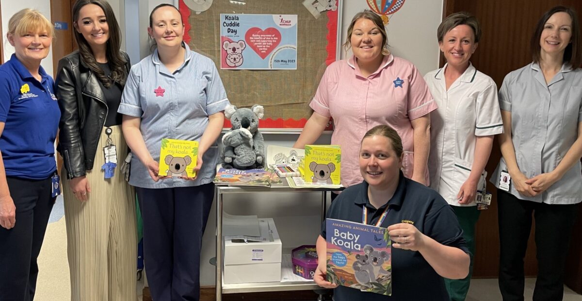Rachel with the congenital heart disease team, holding books and toys about a koala.