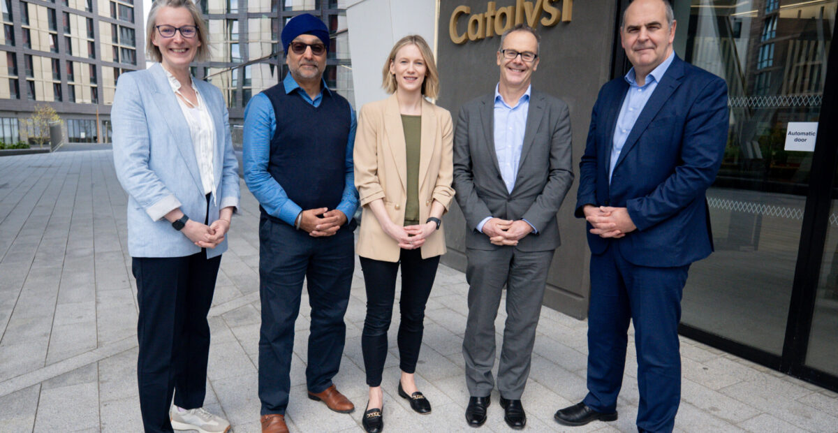 The image shows five people stood in a row outside the entrance to the Catalyst.