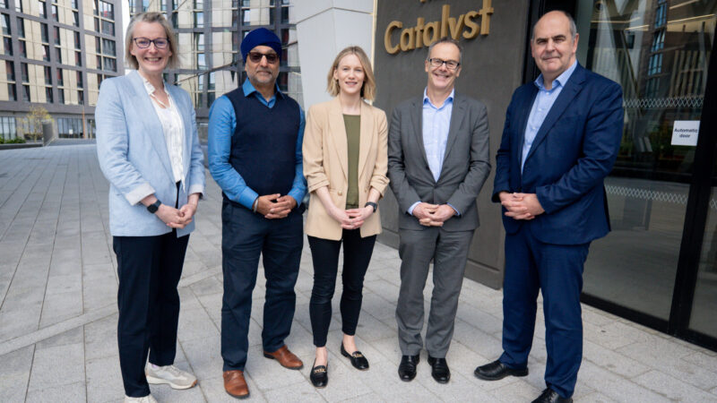 The image shows five people stood in a row outside the entrance to the Catalyst.