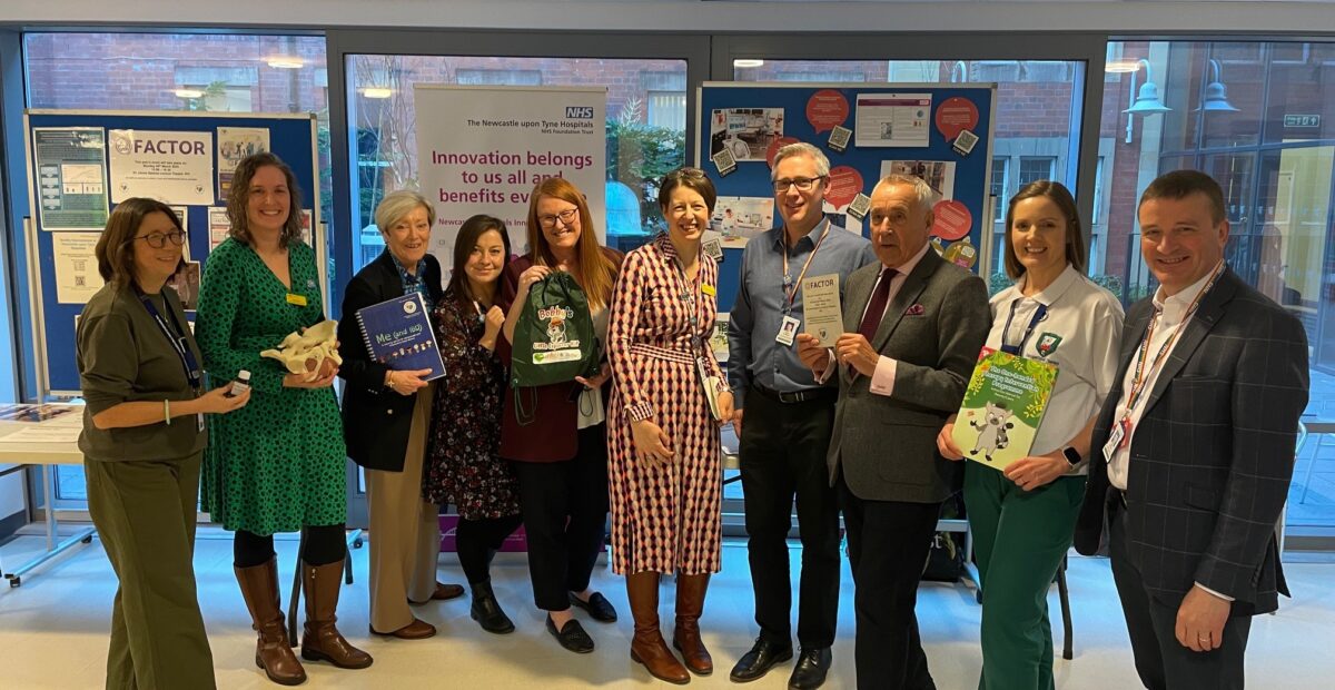 Group of people in front of innovation stand in the RVI, holding books.