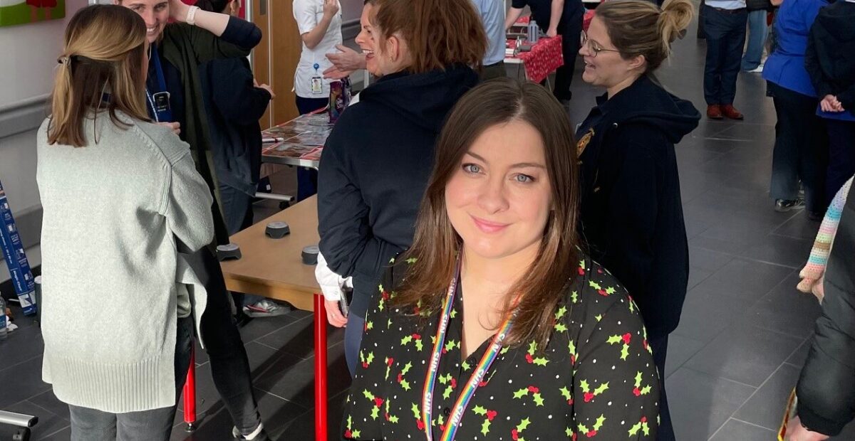 People at an innovation event, with a woman wearing a black, holly christmas top and an NHS lanyard.