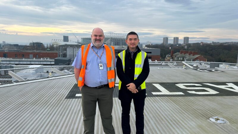 Image show two men standing on the helipad of the hospital