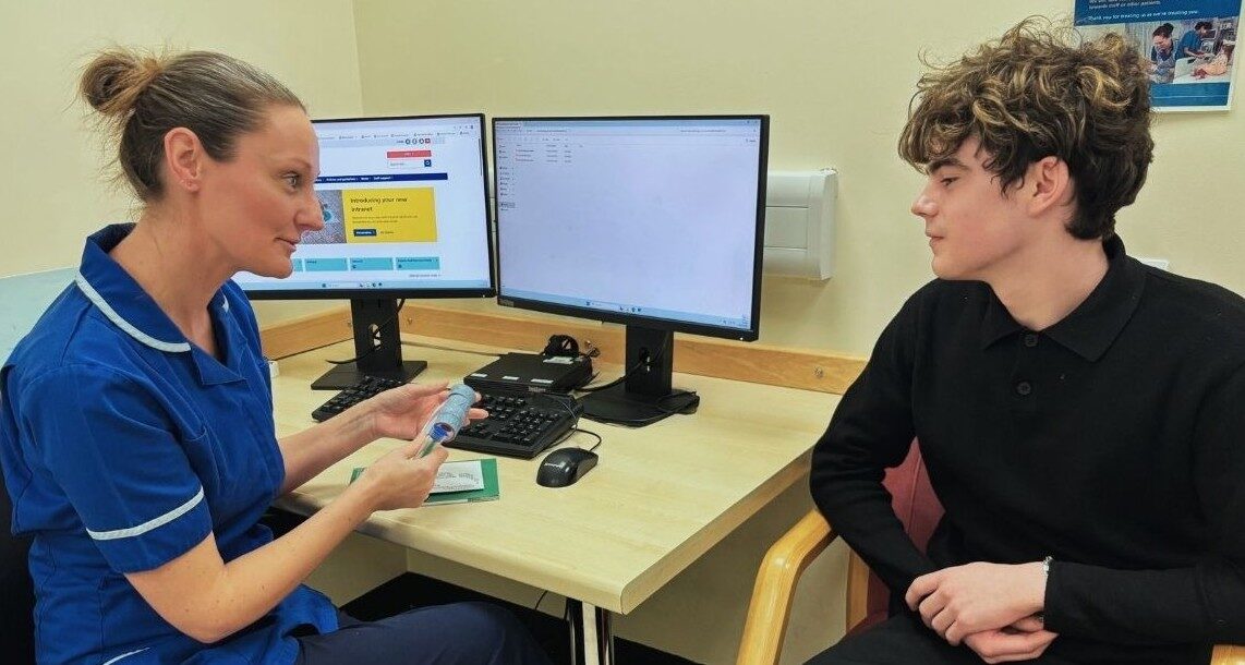 A nurse talking to a patient about their treatment involving Solventum follow-up finder - thrombosis. She is holding a model to describe the condition.
