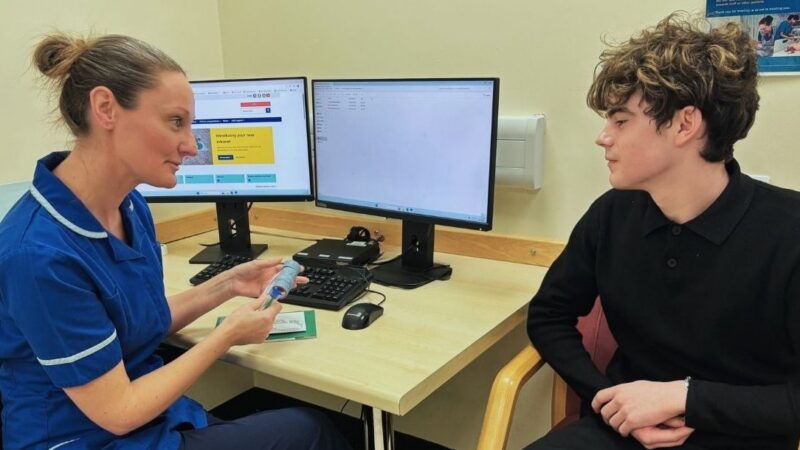 A nurse talking to a patient about their treatment involving Solventum follow-up finder - thrombosis. She is holding a model to describe the condition.