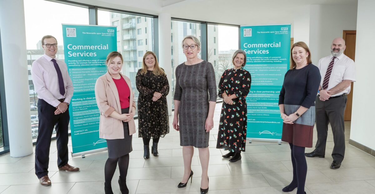 The commercial enterprise team standing together in Regent Point offices with two commercial services banners behind them.