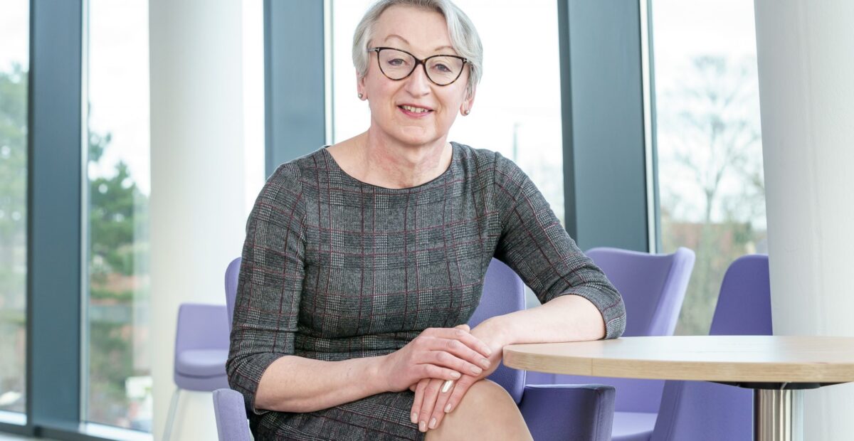 Portrait of Andrea Burroughs sat at a table in the Regent Point offices.
